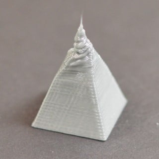 Aşırı sıcaklık nedeniyle üst katmanlarda erime boşalma veya yamukluk sorununu gösteren gri bir piramit modeli